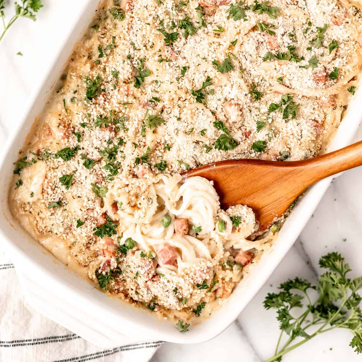 A freshly baked Ham Tetrazzini casserole with a golden breadcrumb topping and steam rising.