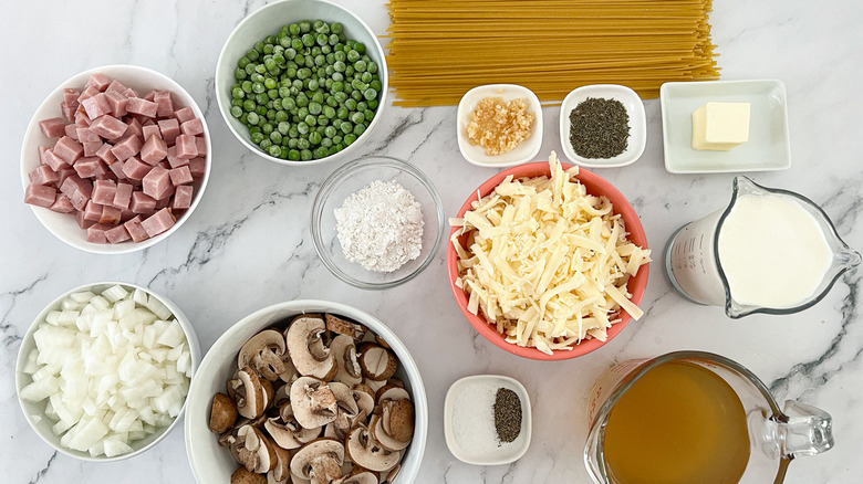 Ingredients for Ham Tetrazzini including diced ham, pasta, sliced mushrooms, and creamy sauce.
